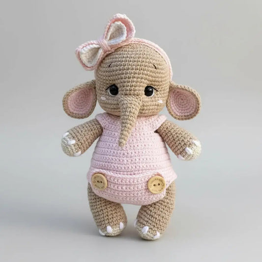Crocheted elephant stuffed animal wearing pink dress with bow and buttons