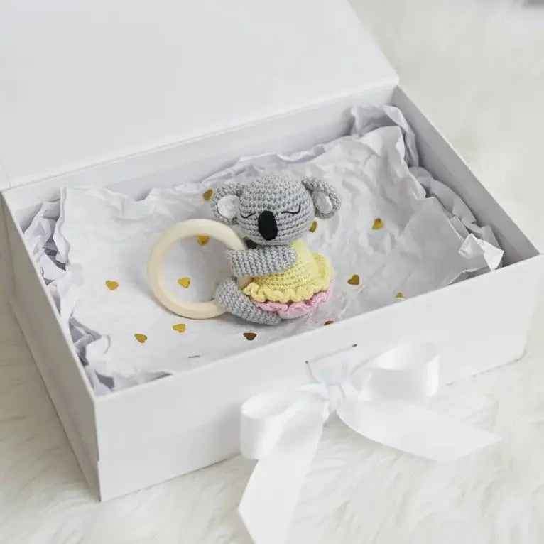 Crocheted koala toy with wooden teething ring in a gift box with heart confetti