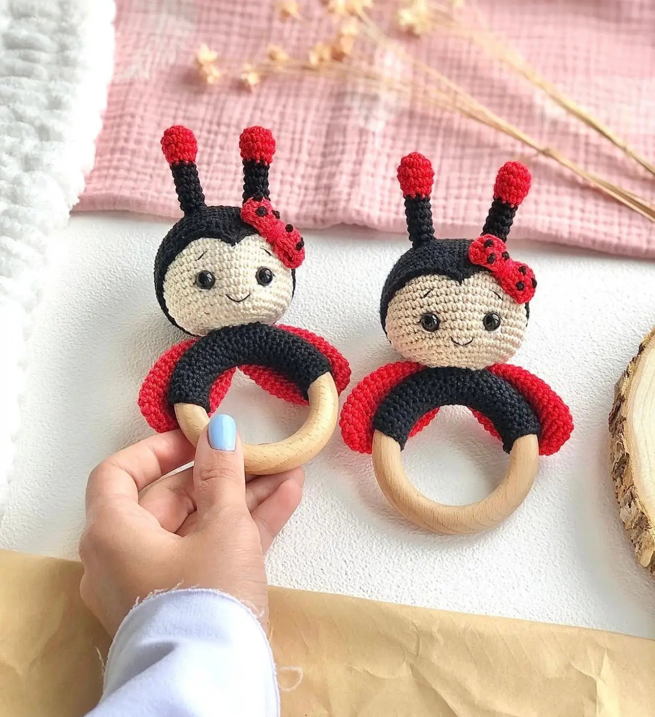 Two crocheted ladybug baby teething rings with wooden circles and cute smiling faces