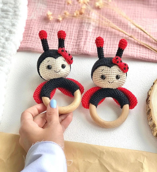 Two crocheted ladybug baby teething rings with wooden circles and cute smiling faces