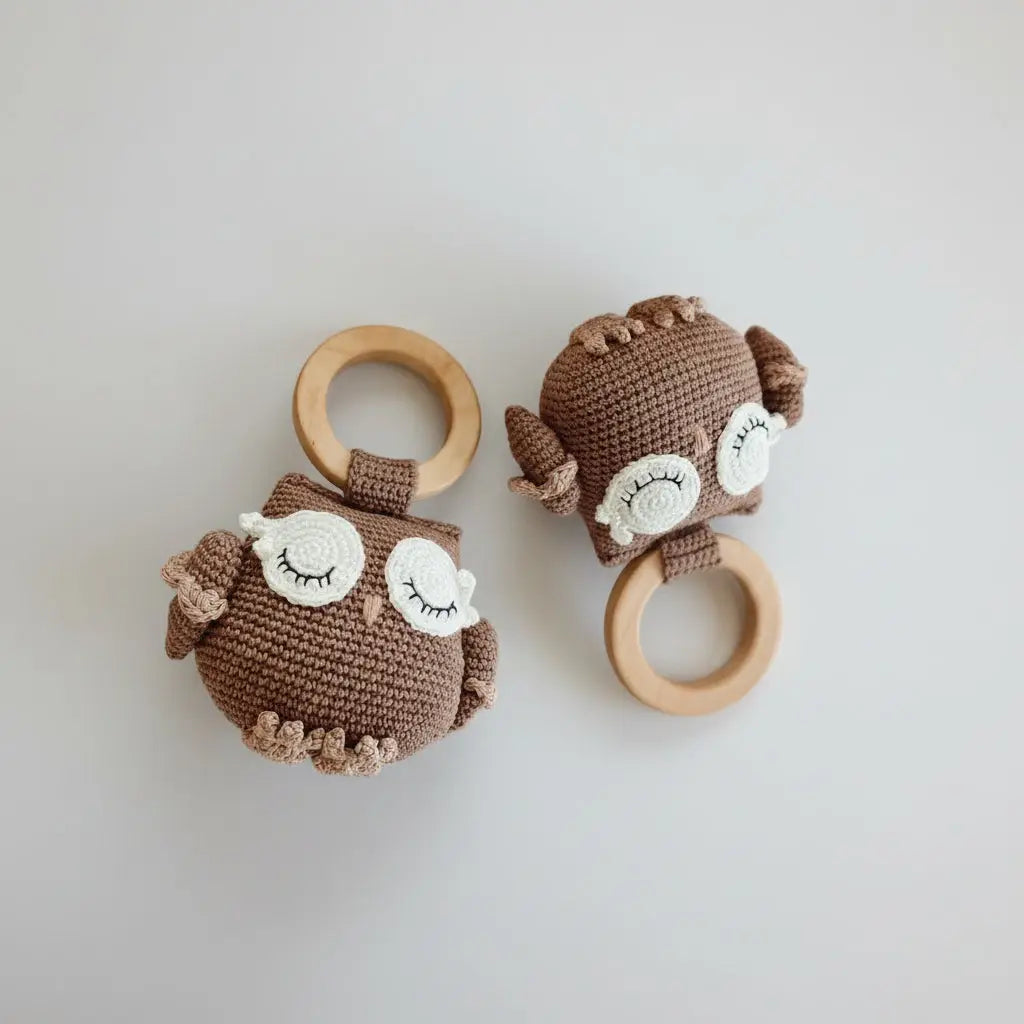 Two brown crochet owl toys with wooden rings on a beige background