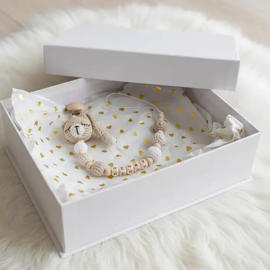 Crocheted bunny and personalized name beads in a white gift box with gold heart pattern