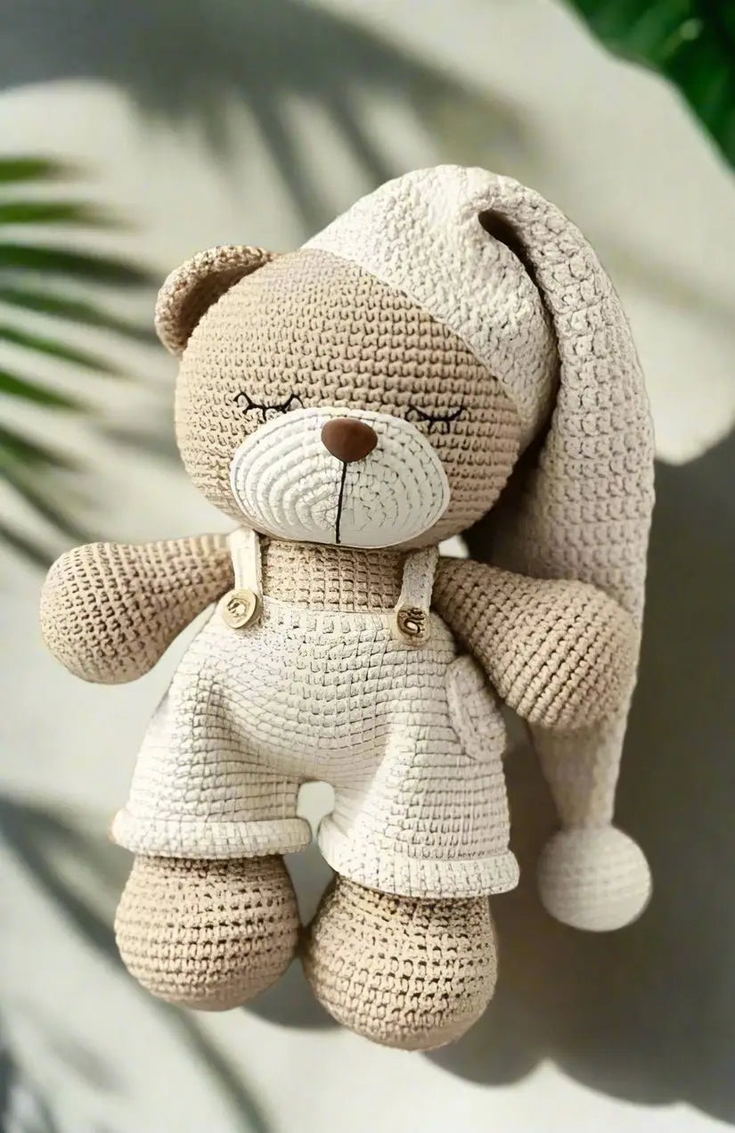 Crocheted teddy bear in cream and beige, sitting with closed eyes and soft texture