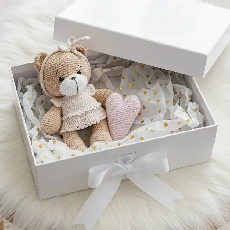 Crocheted teddy bear in gift box with pink heart and gold-dotted tissue paper