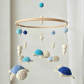 Crocheted turtle baby mobile in blue, white, and navy hanging from wooden ring