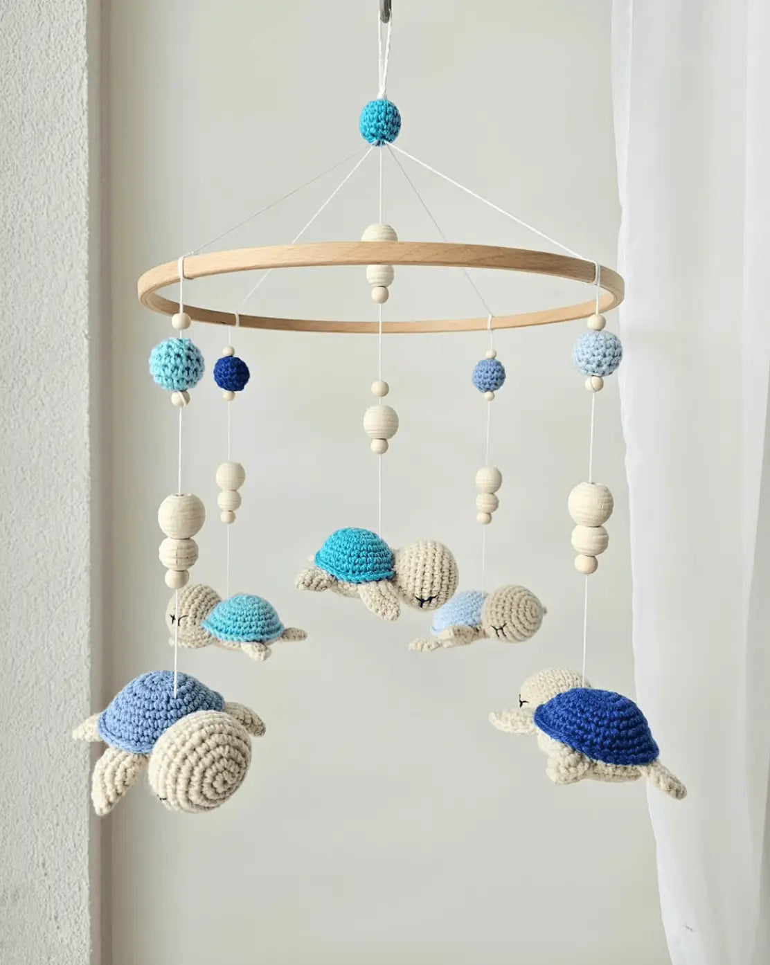 Crocheted turtle baby mobile in blue, white, and navy hanging from wooden ring