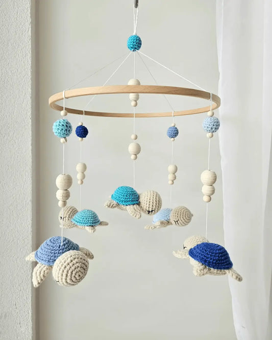 Crocheted turtle baby mobile in blue, white, and navy hanging from wooden ring