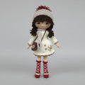 Crocheted doll in white winter outfit with red boots and pom-pom hat