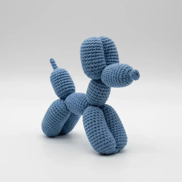 Blue crocheted balloon animal dog sculpture on white background
