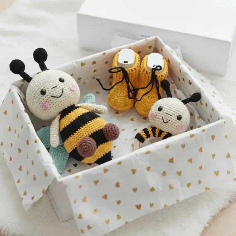 Crocheted bees and baby booties in a white heart-patterned gift box