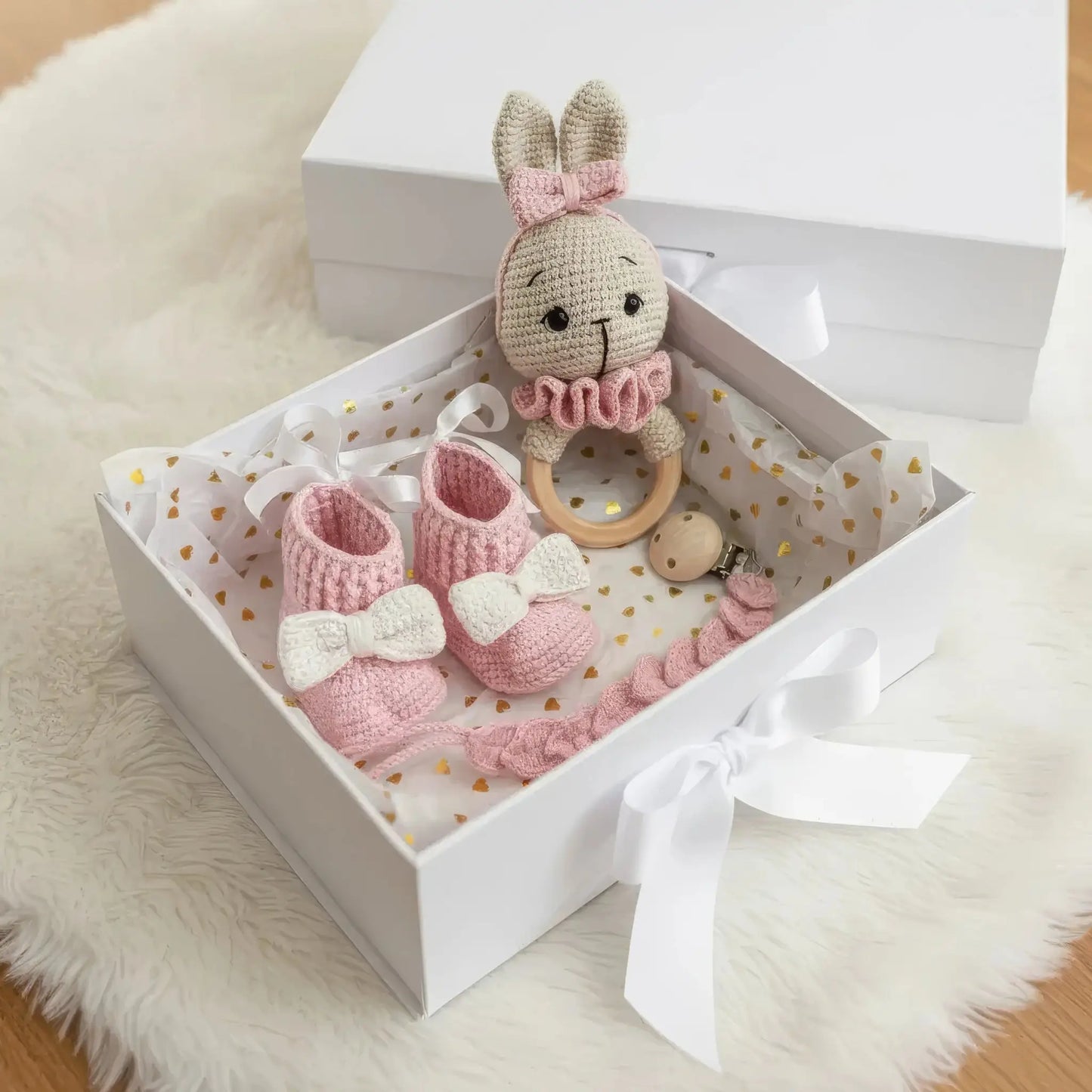 Handmade pink and white crocheted bunny, booties, and teething ring in a gift box