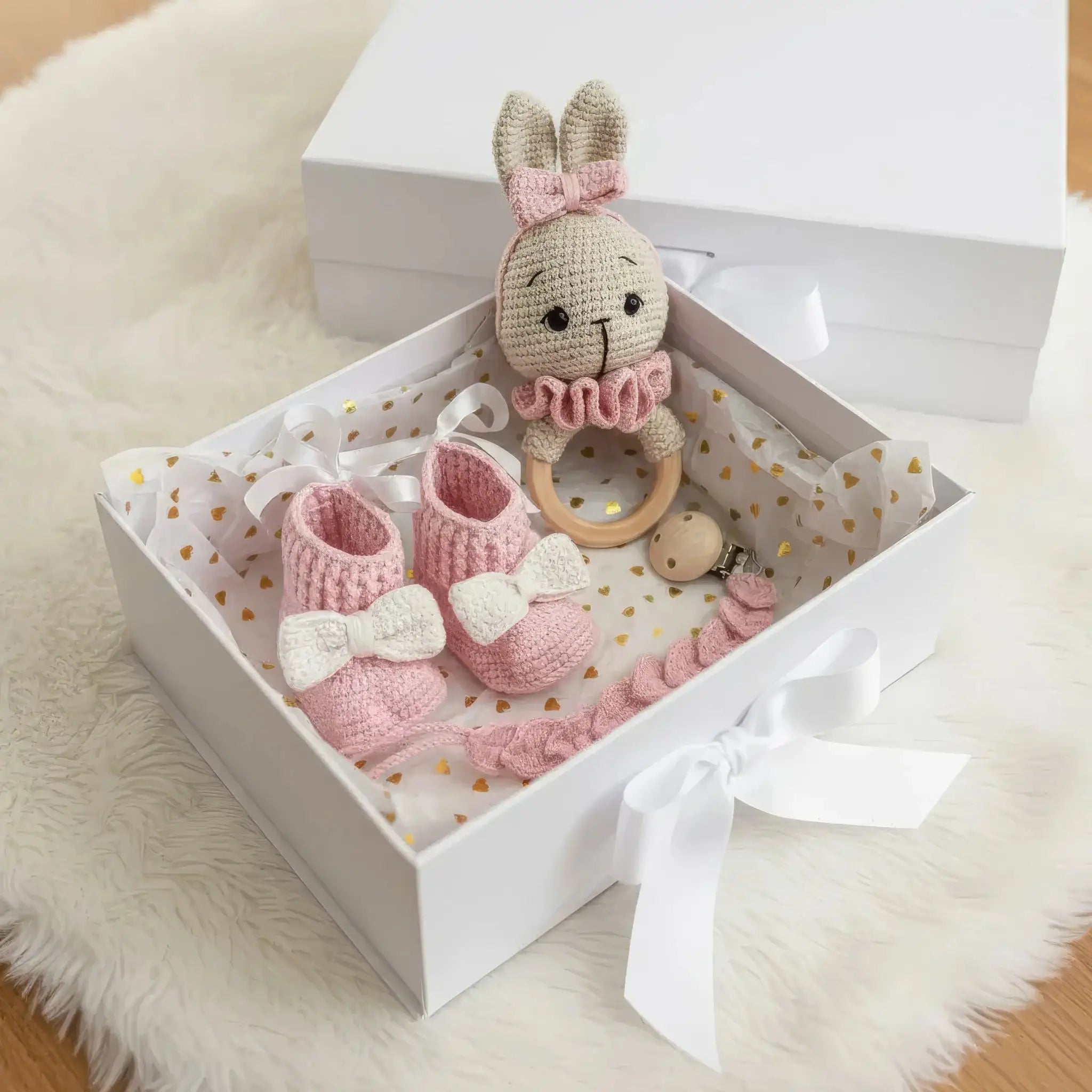 Handmade pink and white crocheted bunny, booties, and teething ring in a gift box