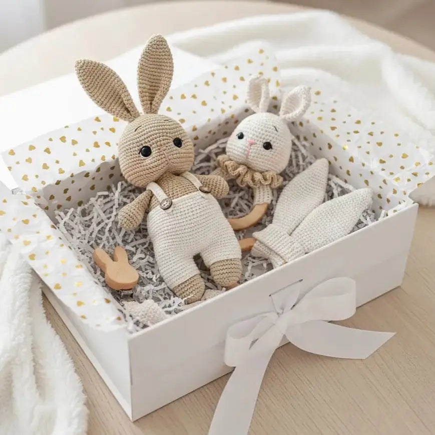 Crocheted bunny dolls in a white gift box with gold hearts and a bow