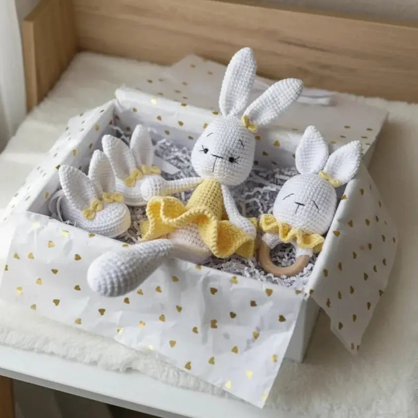 Crocheted white and yellow bunny dolls in a heart-patterned gift box with shredded paper