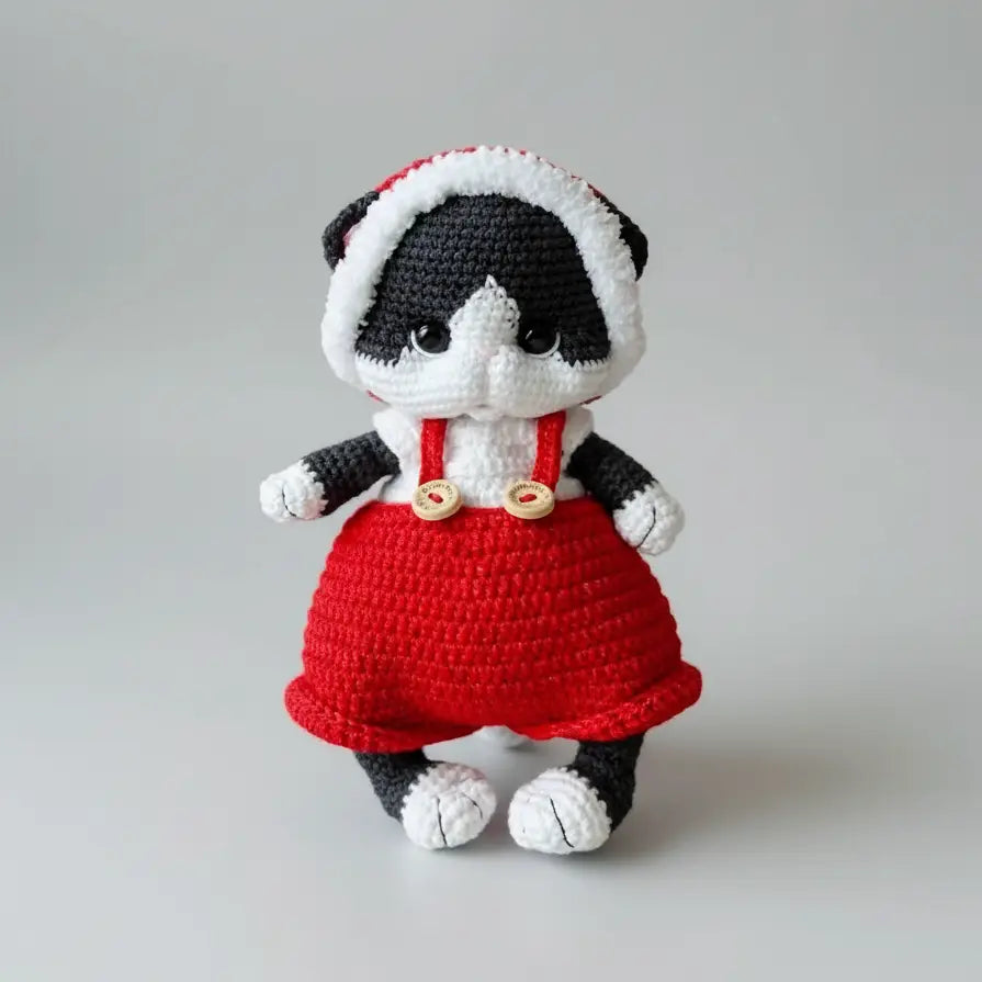 Crocheted panda stuffed animal wearing red overalls and white trim hood