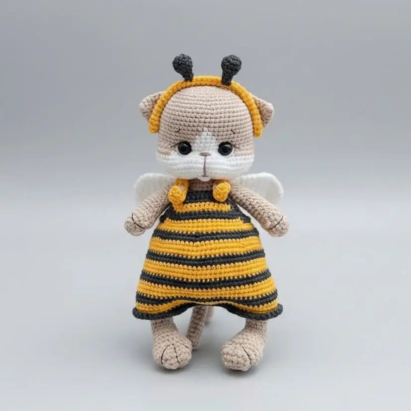 Crocheted stuffed animal in bee costume with yellow and black stripes, white wings