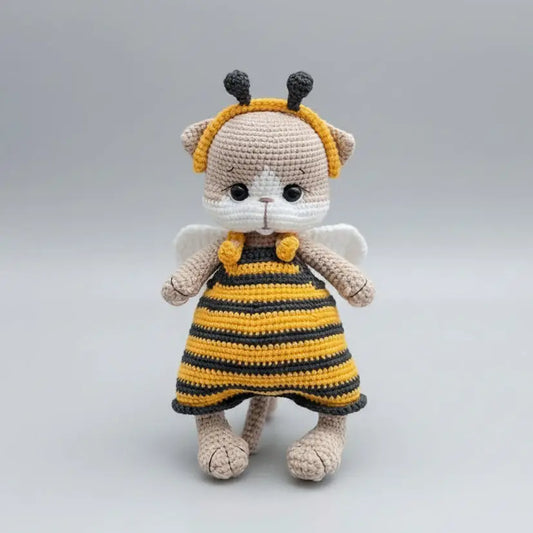 Crocheted stuffed animal in bee costume with yellow and black stripes, white wings