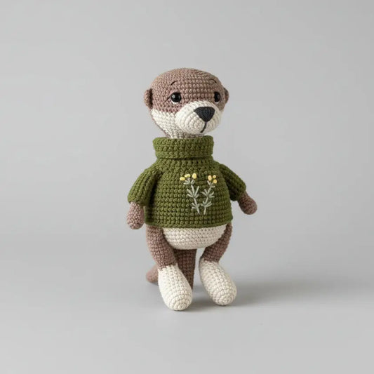 Crocheted otter stuffed animal wearing green sweater with floral embroidery