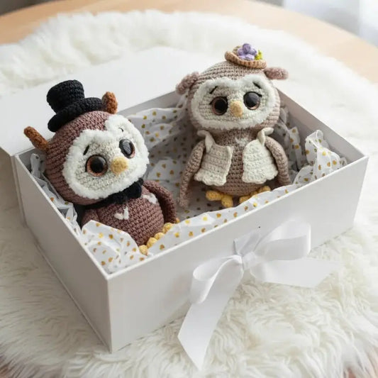 Two crocheted owls in wedding attire nestled in a polka-dot gift box with a white ribbon.