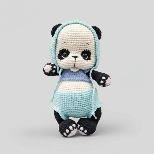 Crocheted panda stuffed animal in blue overalls and hooded top