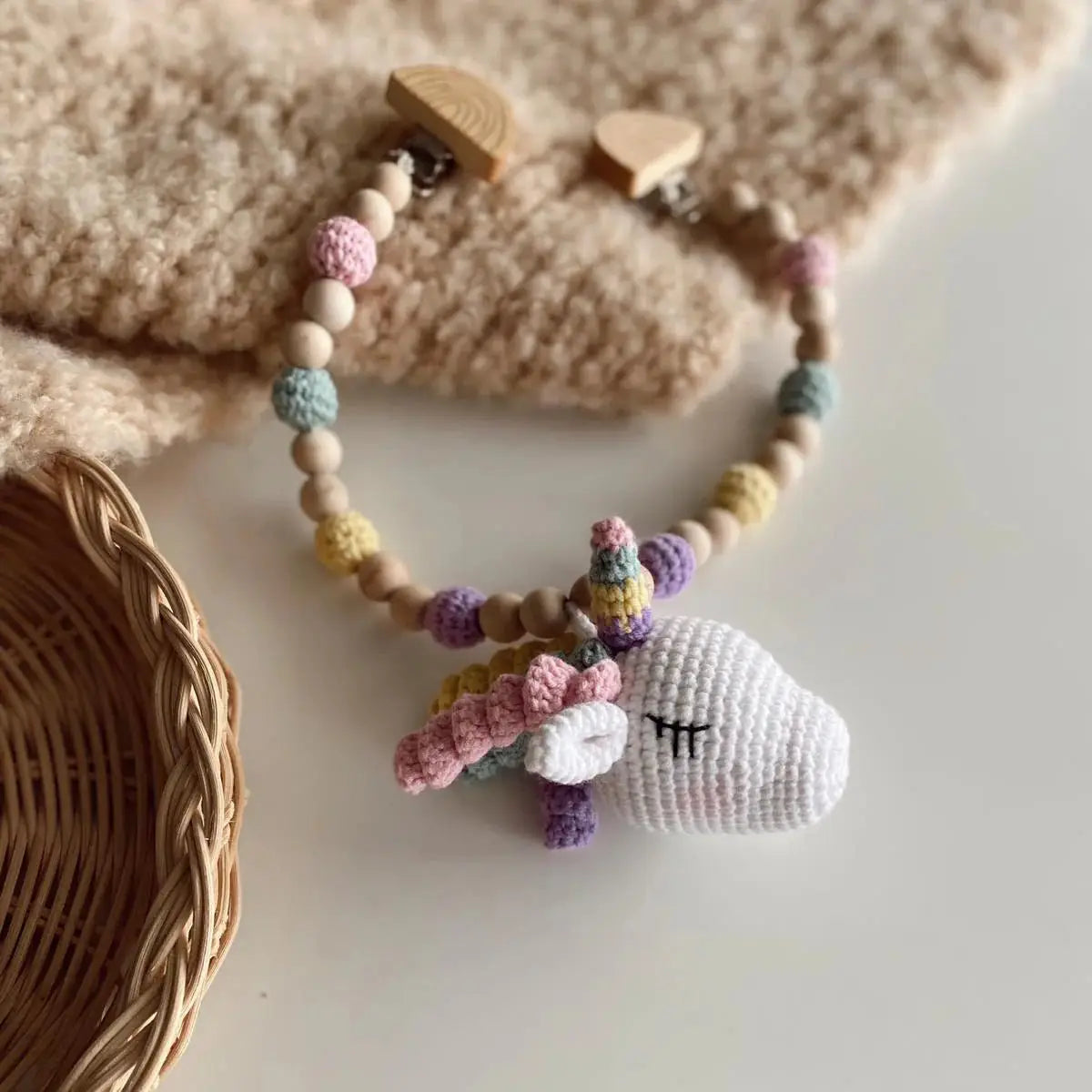 Crocheted pastel unicorn hanging on wooden beaded necklace with woven basket