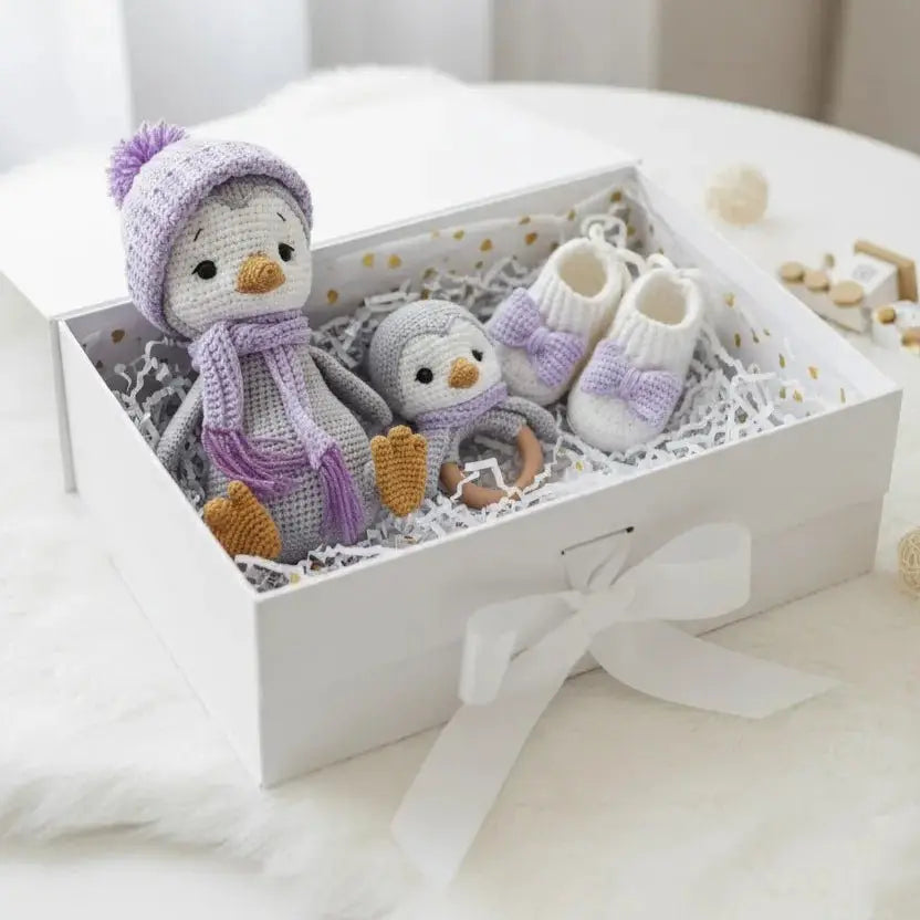 Crocheted penguin toys and baby booties in a white gift box with lavender accents