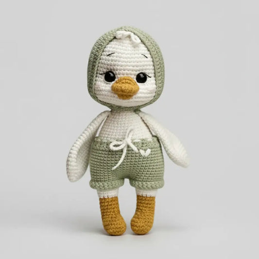 Crocheted penguin stuffed animal in sage green and white with yellow beak and feet