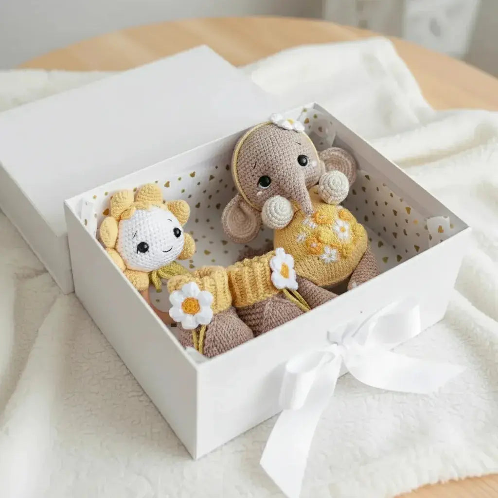 Crocheted elephant and flower friends nestled in a white gift box with ribbon