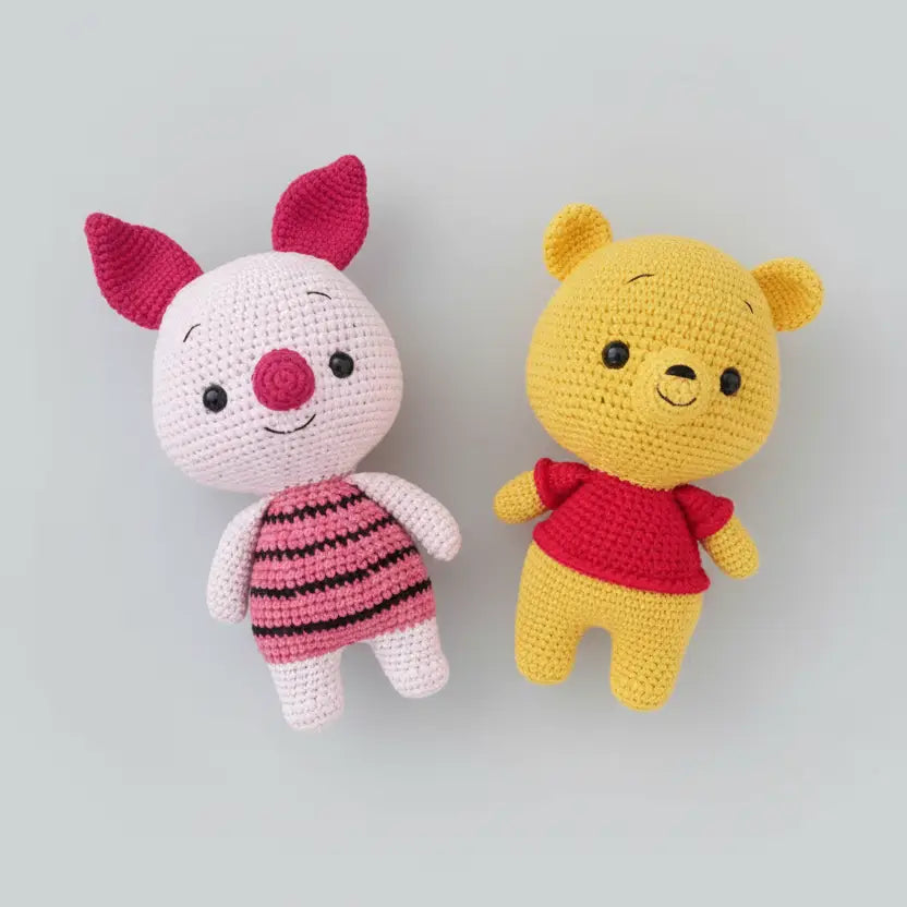 Crocheted Winnie the Pooh and Piglet stuffed toys on gray background