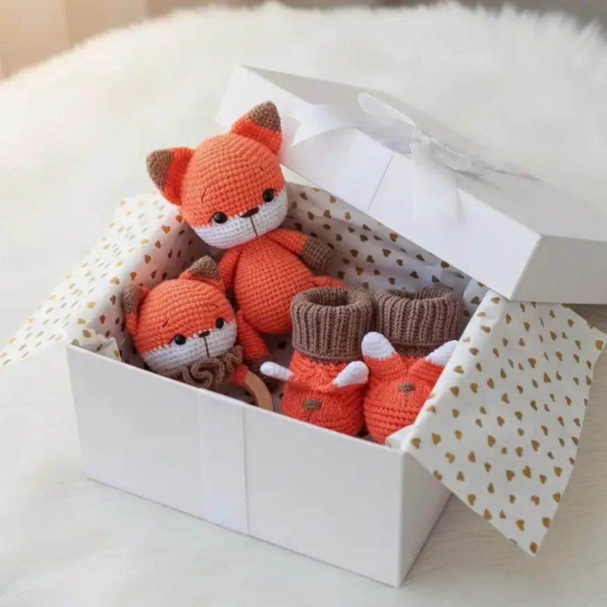 Crocheted orange fox dolls and booties nestled in a polka-dot gift box with white lid