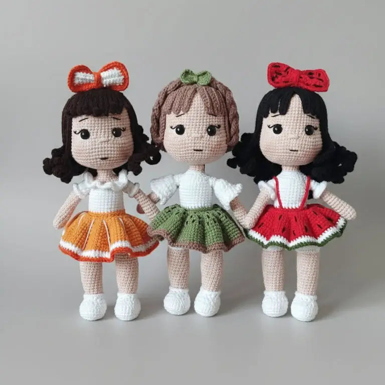Three crocheted dolls with curly hair and bows, wearing colorful skirts and white tops