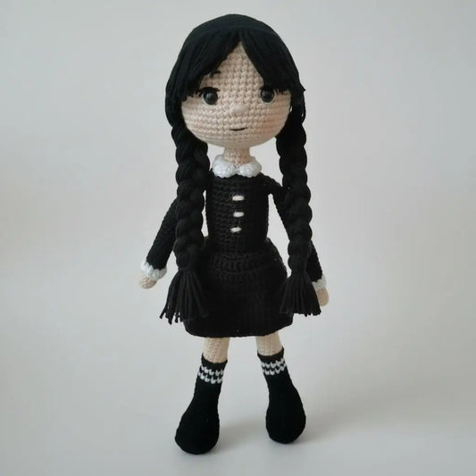 Crocheted doll with black braids wearing a dark dress and white collar