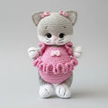 Crocheted gray and pink cat plush with adorable ruffled dress and bow details