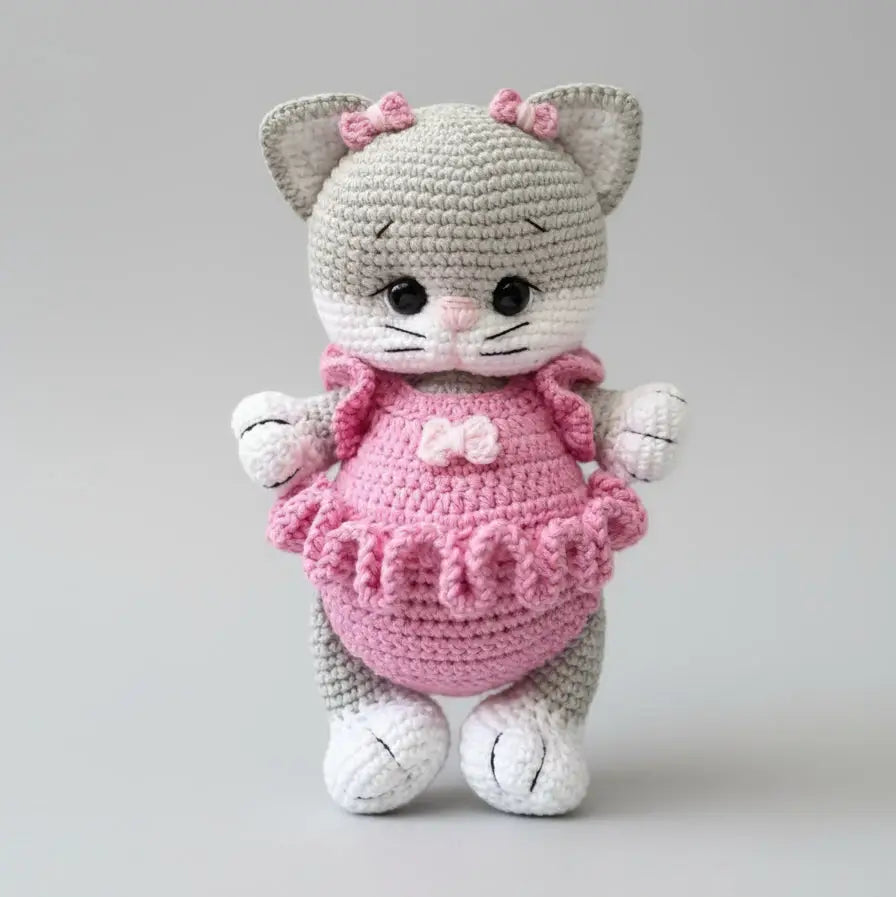 Crocheted gray and pink cat plush with adorable ruffled dress and bow details
