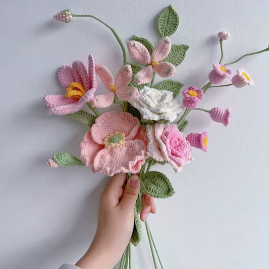 Delicate crocheted flower bouquet in soft pink, white, and green hues held by a hand