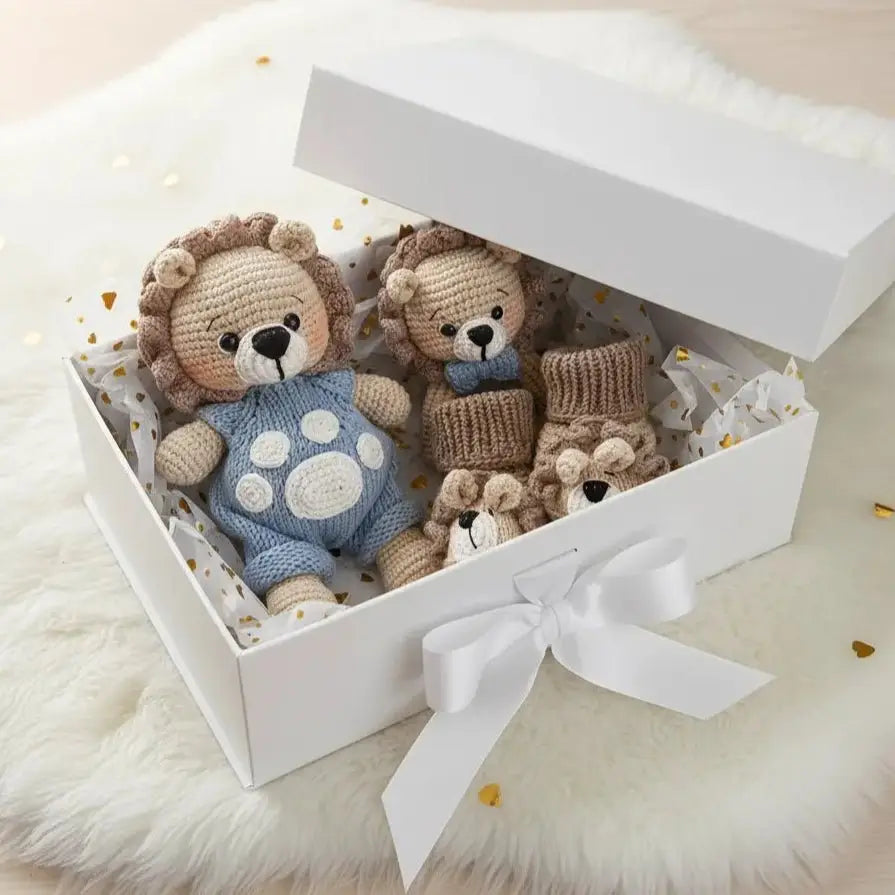 Three crocheted lion stuffed animals nestled in a white gift box with a ribbon