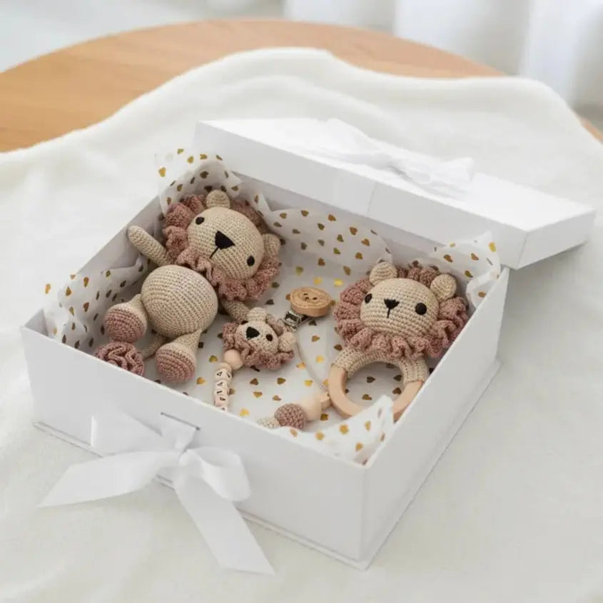 Crocheted lion baby toys and teething ring in a white gift box with gold dots