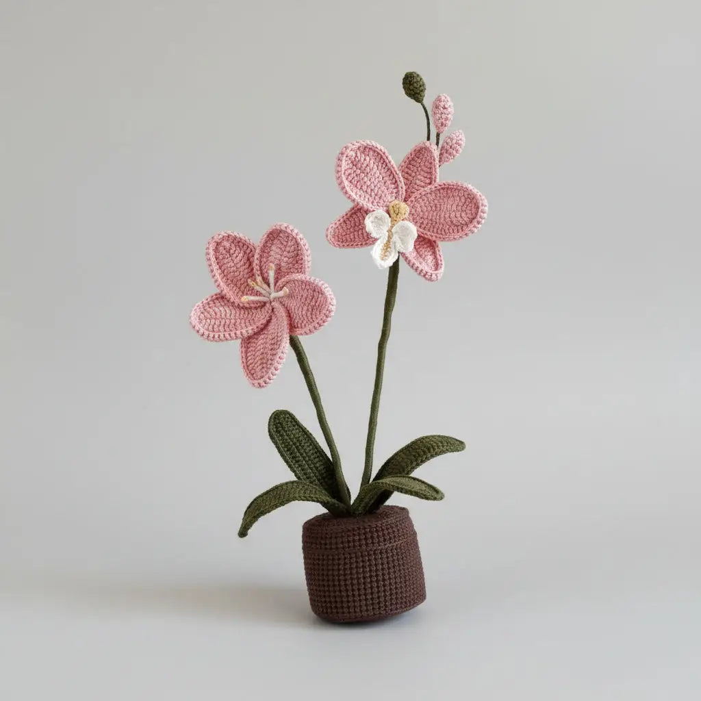 Crocheted pink orchid with green leaves in a brown textured pot against neutral background