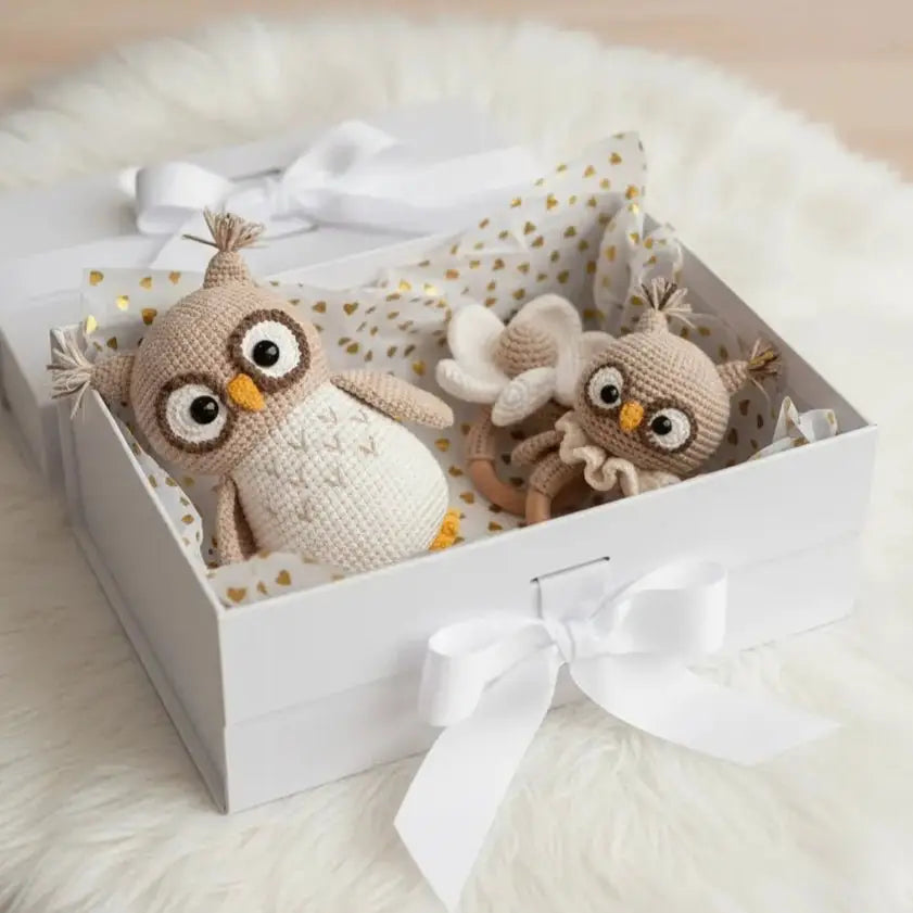 Two crocheted owl toys nestled in a white gift box with gold-dotted lining and a white bow.
