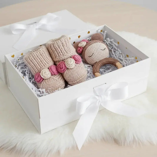 Handmade knitted baby toys with pink flowers in a white gift box with ribbon