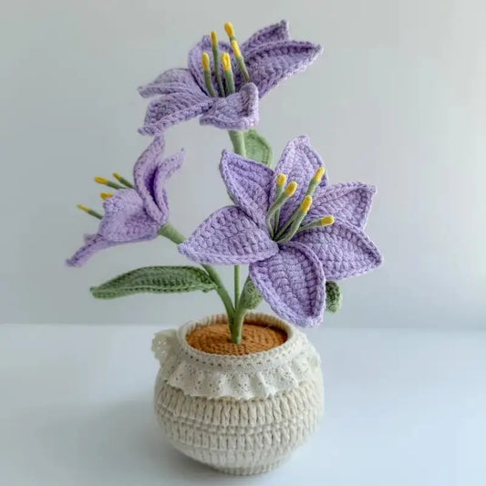 Crocheted lavender lilies with yellow stamens in a textured white ceramic pot