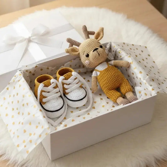 Crocheted deer doll and baby sneakers in a white gift box with gold polka dot lining