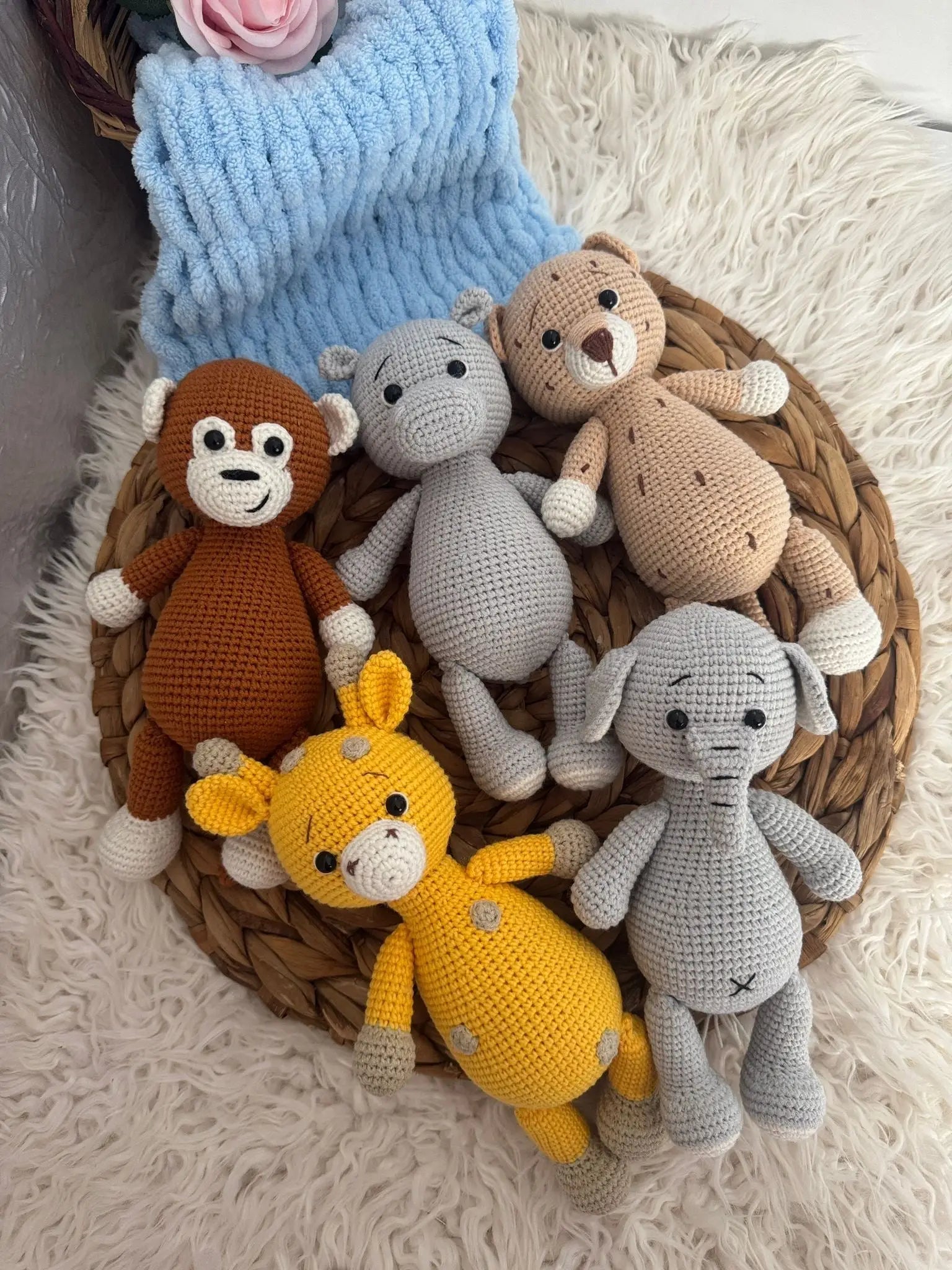Crocheted stuffed animals in brown, yellow, gray, and beige sitting in a woven basket.
