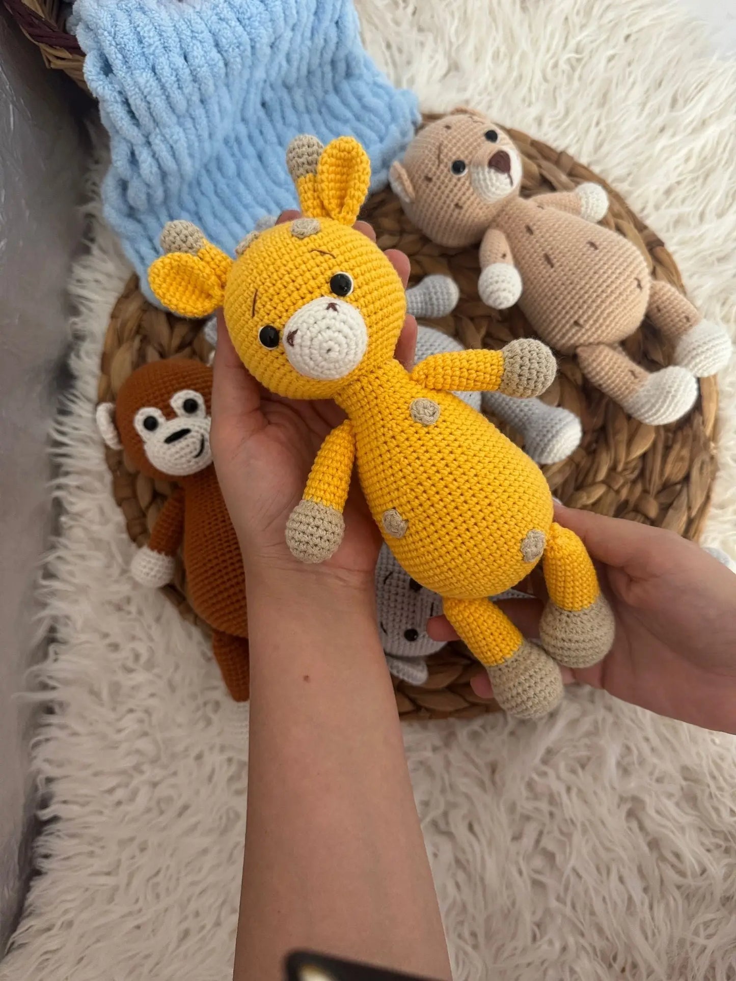 Crocheted yellow and tan stuffed animal toys in a basket, with a blue knitted item nearby