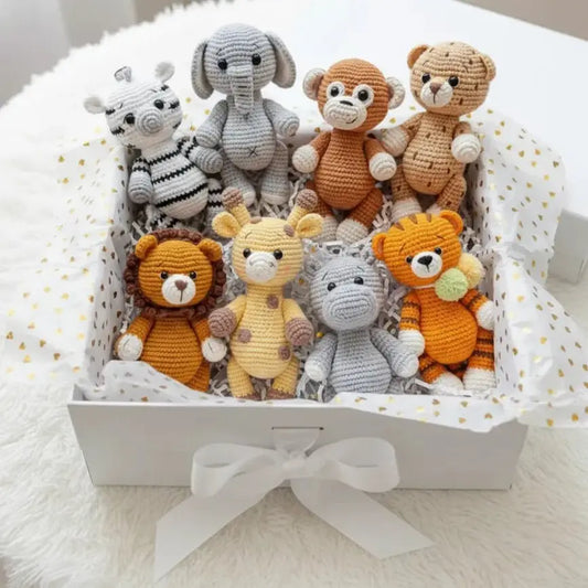 Collection of crocheted safari animal stuffed toys nestled in white gift box with gold dots