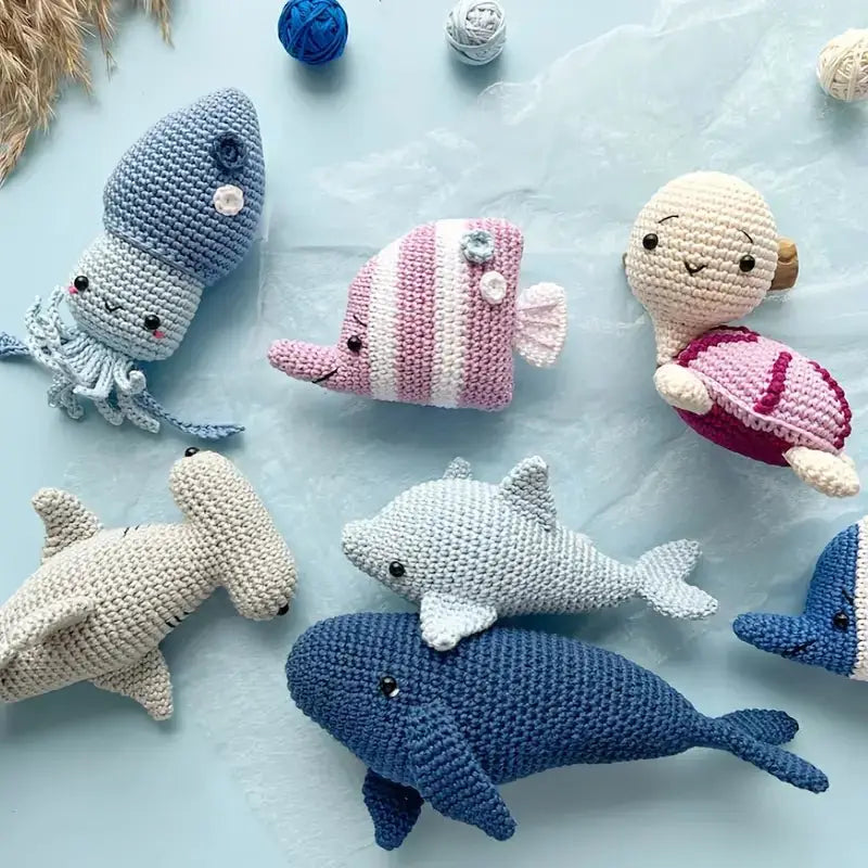 Crocheted sea creatures in blue, pink, and white on a light blue background