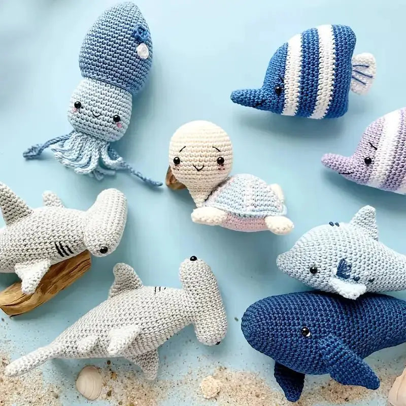 Crocheted sea creatures in blue, white, and gray tones on a light blue background