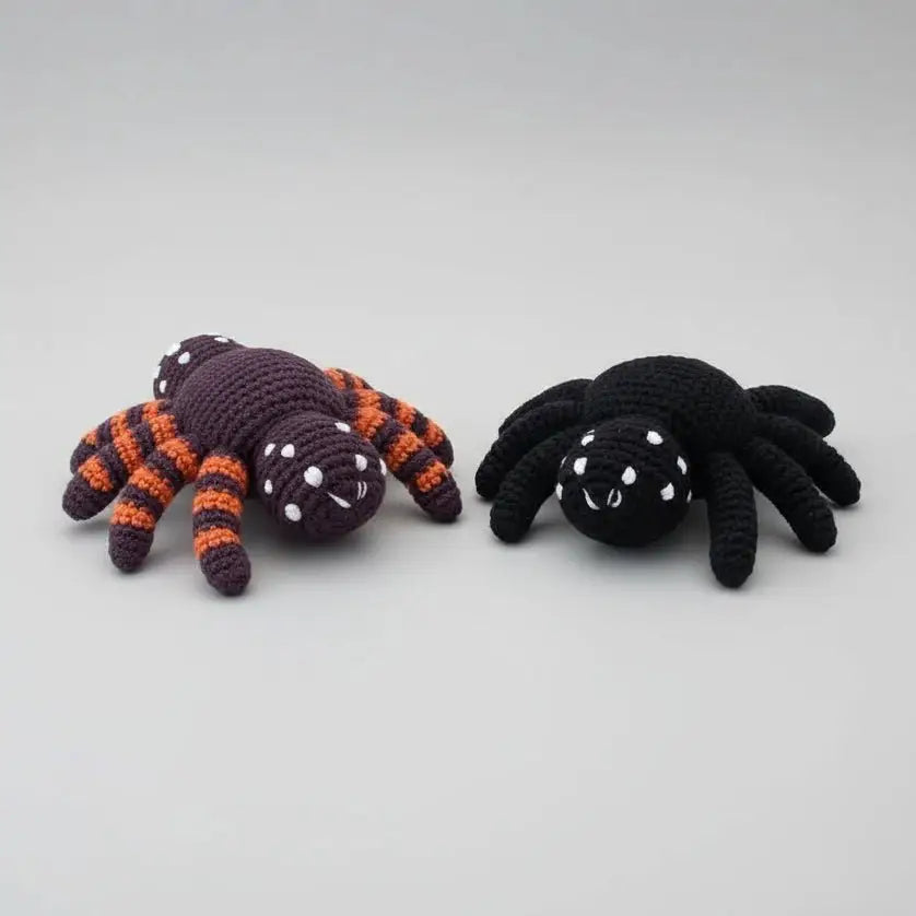 Two crocheted spiders - one purple and orange, one black - with white dot eyes