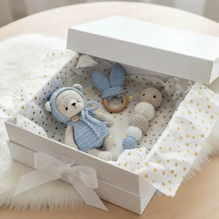 Crocheted blue and cream baby toys in a gift box with gold heart pattern