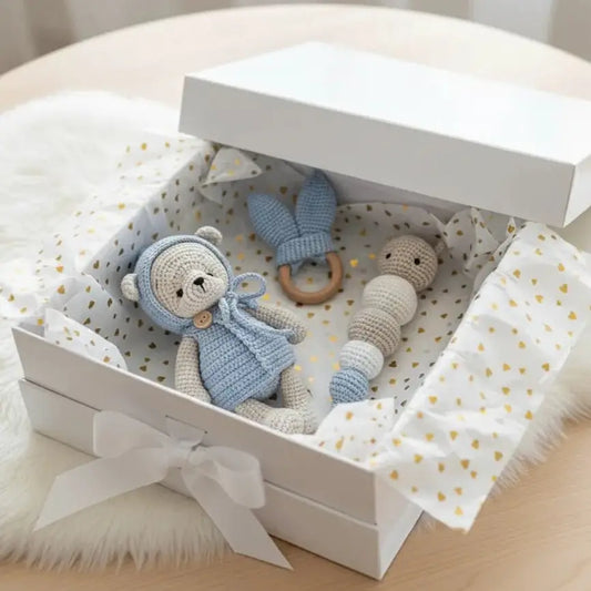 Crocheted blue and cream baby toys in a gift box with gold heart pattern